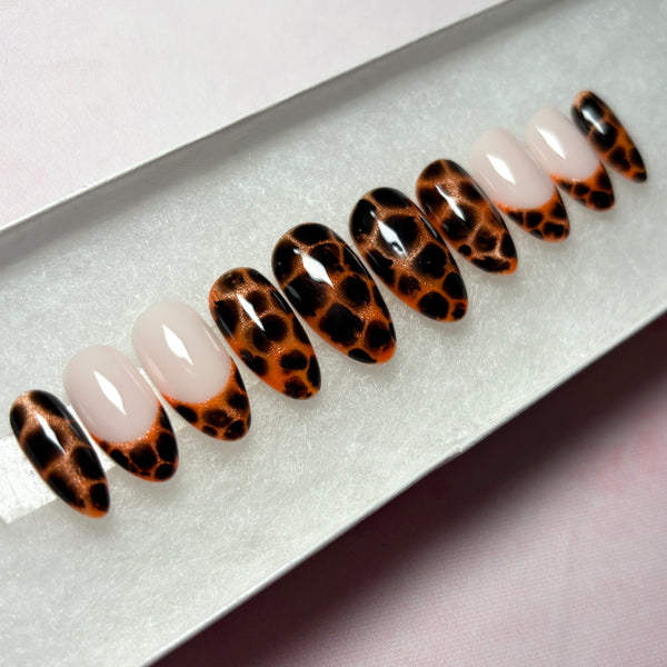 Load image into Gallery viewer, Animal print false nails with a design that resembles leopard print or tortoiseshell in copper and deep brown-black, as well as four French tip nails tipped with the same animal print pattern, displayed in a white presentation box.
