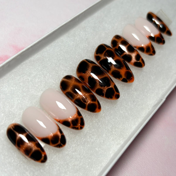 Load image into Gallery viewer, A set of handmade press-on nails featuring an animal print design that resembles leopard print or tortoiseshell in copper and deep brown-black, as well as four French tip nails tipped with the same animal print pattern, displayed in a white presentation box.
