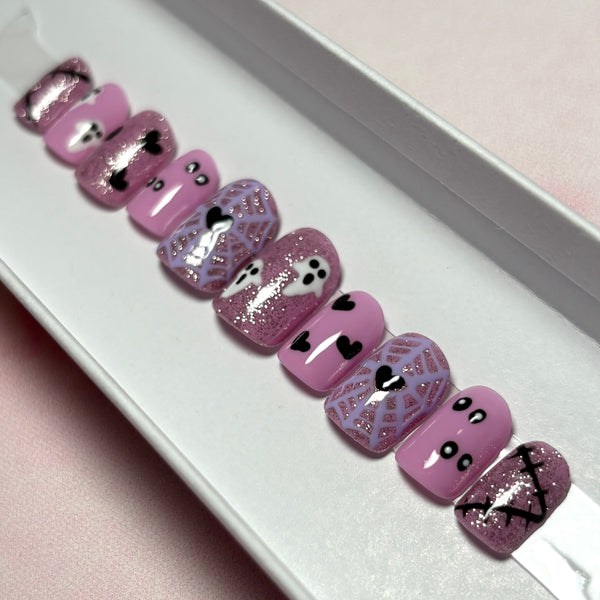 Load image into Gallery viewer, Short Halloween press-on nails featuring pink glitter, lavender spiderwebs with black hearts at their centres, white ghosts, and black hearts and scars, handmade by Illuminate by Liana Press-On Nails UK.
