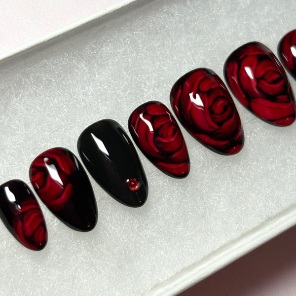 Load image into Gallery viewer, Gothic or dark romance style press-on nails with 3D effect roses in dark red and delicate red rhinestones, in a short almond shape, displayed in a white presentation box.
