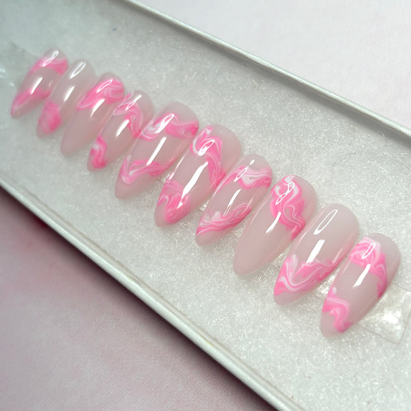 Load image into Gallery viewer, Soft pink press-on nails in a long almond shape with swirls of pink and white marble effect on each nail, displayed in a white presentation box, created by Illuminate by Liana UK
