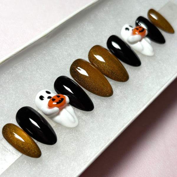 Load image into Gallery viewer, Halloween press-on nails featuring 3D white ghosts holding 3D orange jack-o'-lantern pumpkins, in glossy black and coppery glittery gold cat eye, handmade by Illuminate by Liana Press-On Nails UK.

