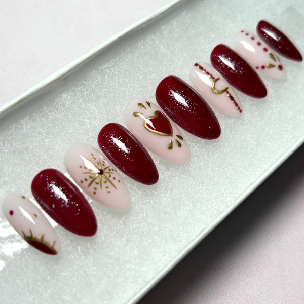 Load image into Gallery viewer, Handmade press-on nails in deep red and natural pink with celestial and heart designs in red and gold chrome including gold stars, a crescent moon, sun and tattoo style dots.
