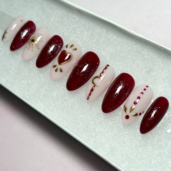 Load image into Gallery viewer, Red bohemian design press-on nails in deep red, natural pink and gold, with celestial and heart designs including gold chrome stars, a crescent moon, sun and henna style dots.
