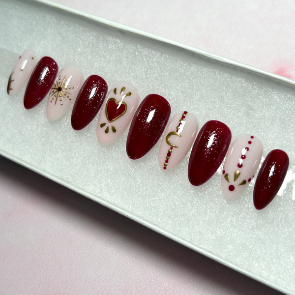 Load image into Gallery viewer, Short almond press-on nails in deep red and natural pink with bohemian designs in red and gold chrome including gold stars, a crescent moon, sun and tattoo style dots.
