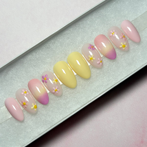 Load image into Gallery viewer, Spring summer design floral press-on nails in soft pastel yellows and pinks with delicate pastel flowers in pinks and whites and an ombre design, in a white presentation box. 
