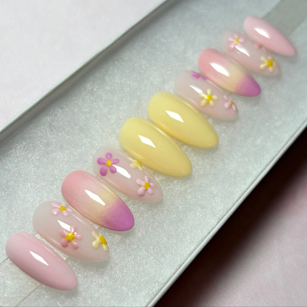 Load image into Gallery viewer, Spring Summer press-on nails in soft pastel yellows and pinks decorated with delicate pastel flowers in pinks and whites and an ombre design, in a short almond shape.
