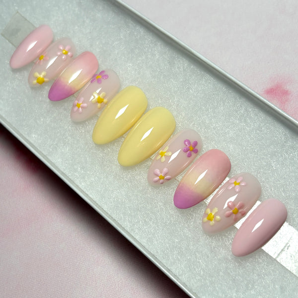 Load image into Gallery viewer, Summer floral press-on nails in soft pastel yellows and pinks with delicate pastel flowers in pinks and whites and an ombre design, in a white presentation box. 
