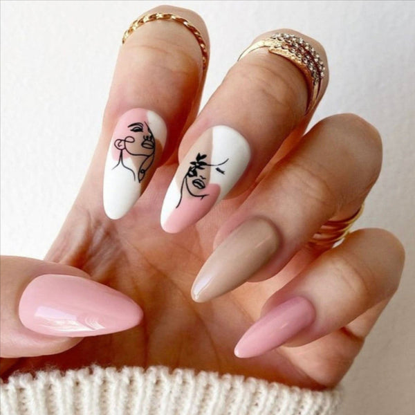 Load image into Gallery viewer, Hand wearing handmade press-on nails in beige and pink with abstract faces designs
